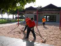 Men grating sand in front of building