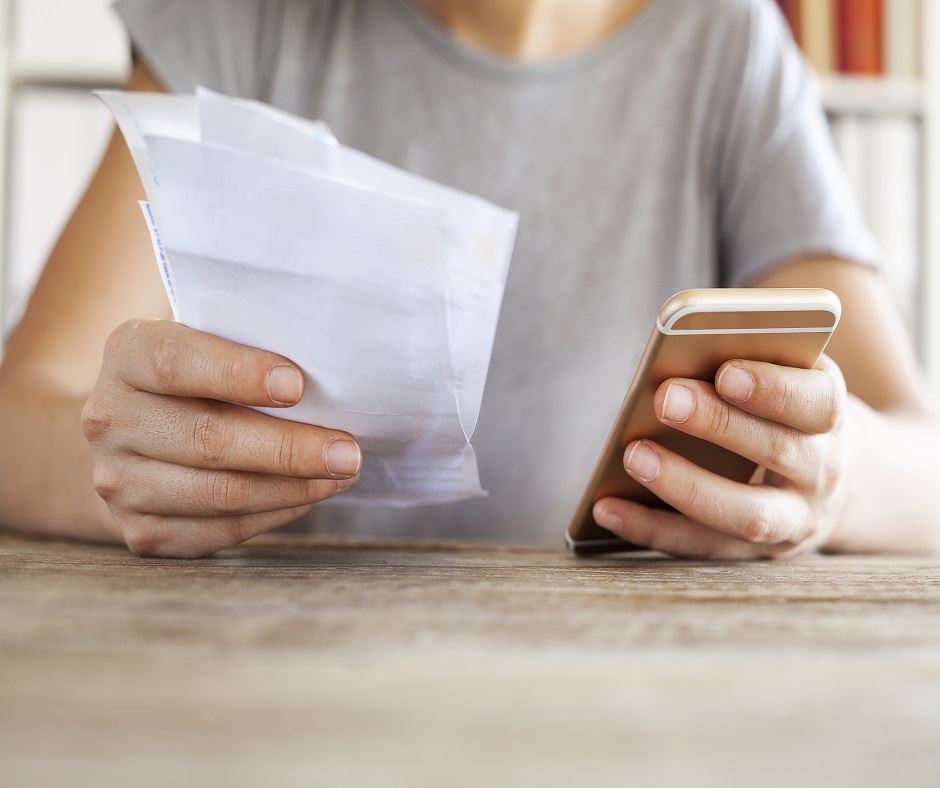 Woman uses cell phone to pay bills